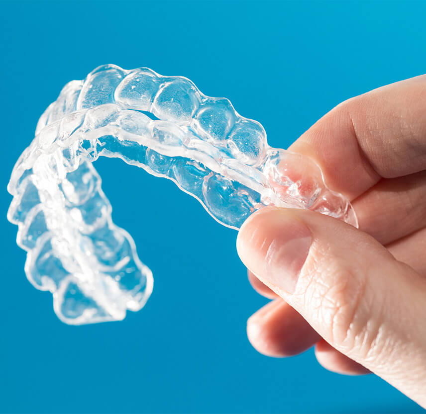 closeup of a hand holding a set of clear aligners