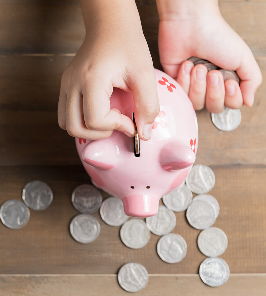 hands putting coins in a piggy bank
