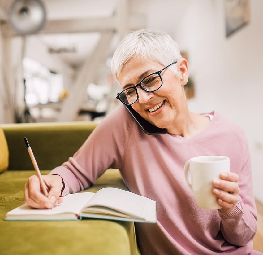 woman writing something down while on a phone call