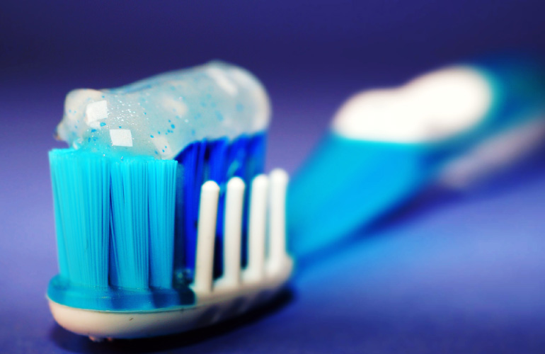 Photo of a blue toothbrush loaded with sparkly toothpaste.