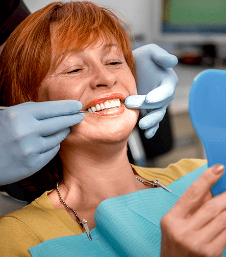 woman at dentist smiling into mirror