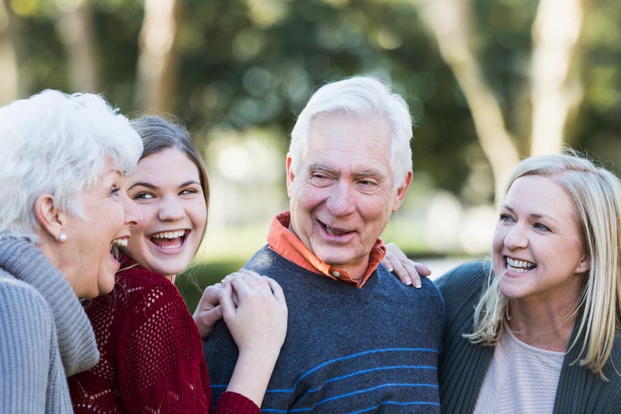 Smiling and laughing older couple with a daughter and granddaughter.