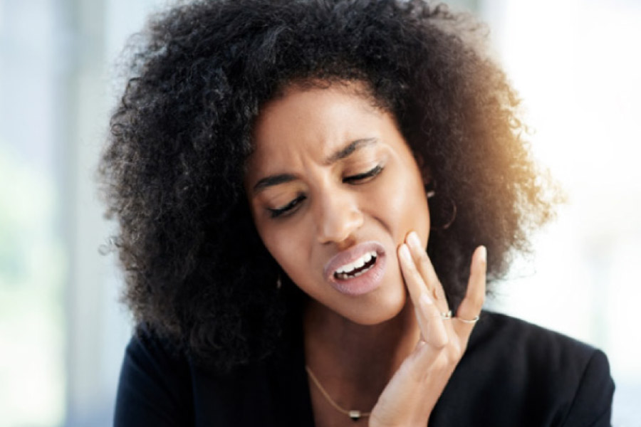 woman holds her jaw in pain with a dental emergency.