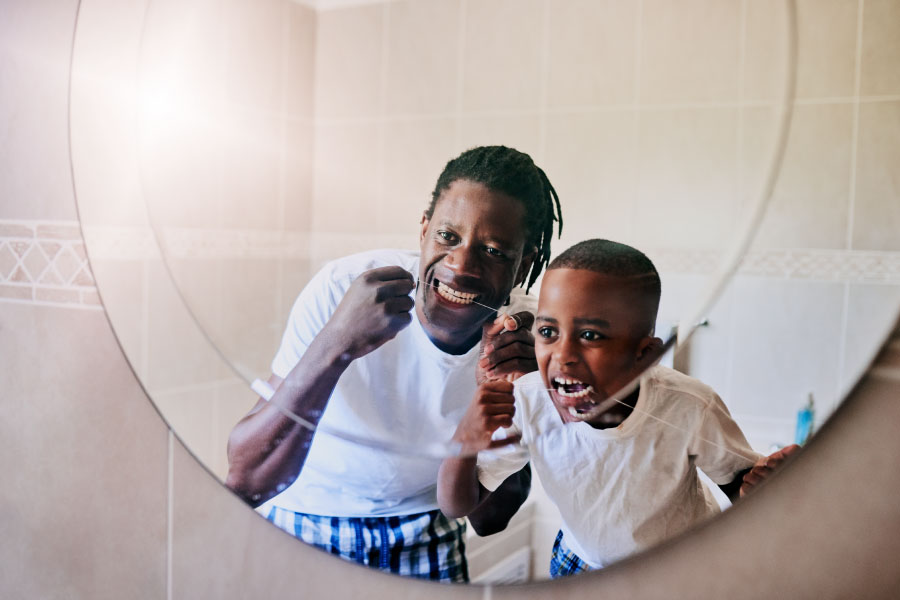 father and young son flossing their teeth together