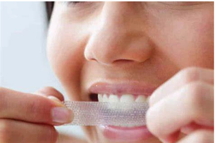 woman applying whitening strips to her teeth